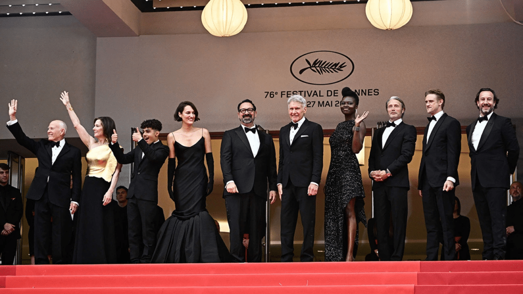 Parte do elenco e da equipe de produção de Indiana Jones e a Relíquia do Destino saudando o público no tapete vermelho do Festival de Cannes. Foto de Loic Venance/AFP via Getty Images.